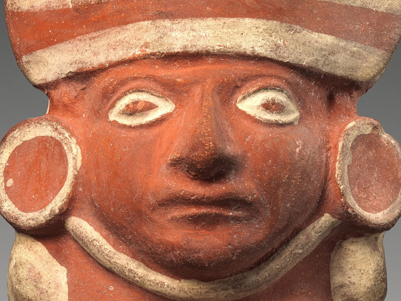 Detail of a ceramic vessel made by a Moche artist. This detail shows the neck of the vessel which is modeled to look like a human head wearing a hat and earspools.